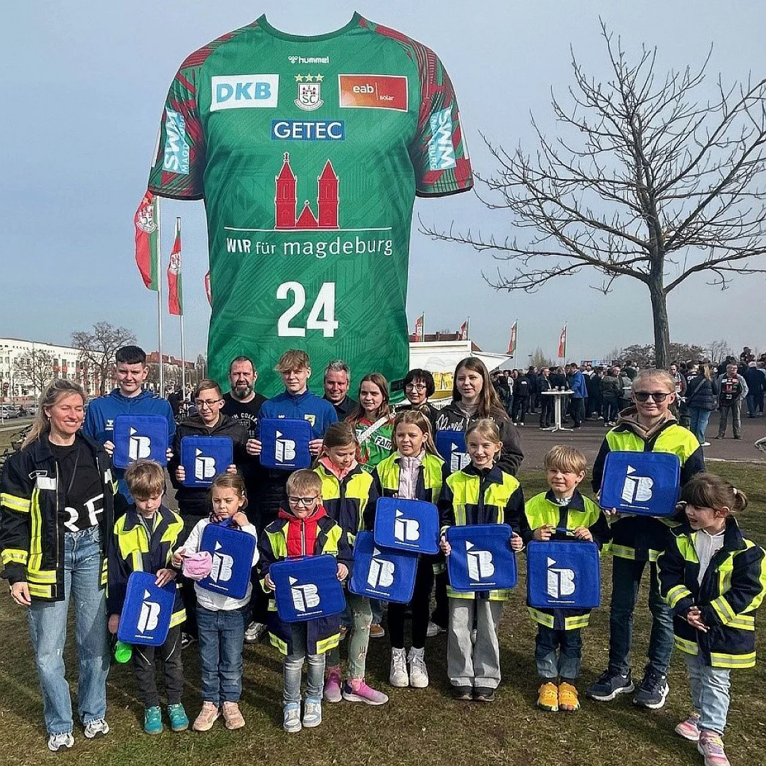 Mitglieder und Betreuer der Kinderfeuerwehr Nedlitz mit IB-Sitzkissen in der Hand vor der Getec-Arena in Magdeburg