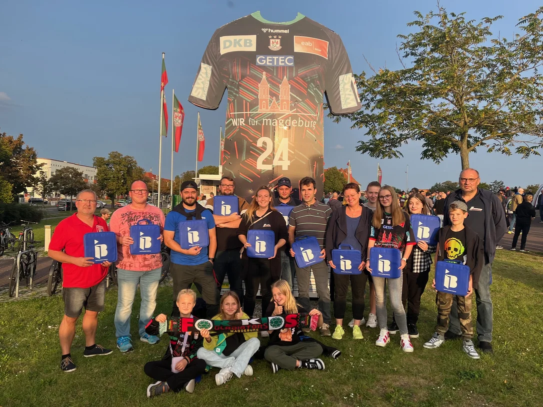 Mitglieder der freiwilligen Feuerwehr Biere mit IB-Logos in der Hand vor einer Arena in Magdeburg