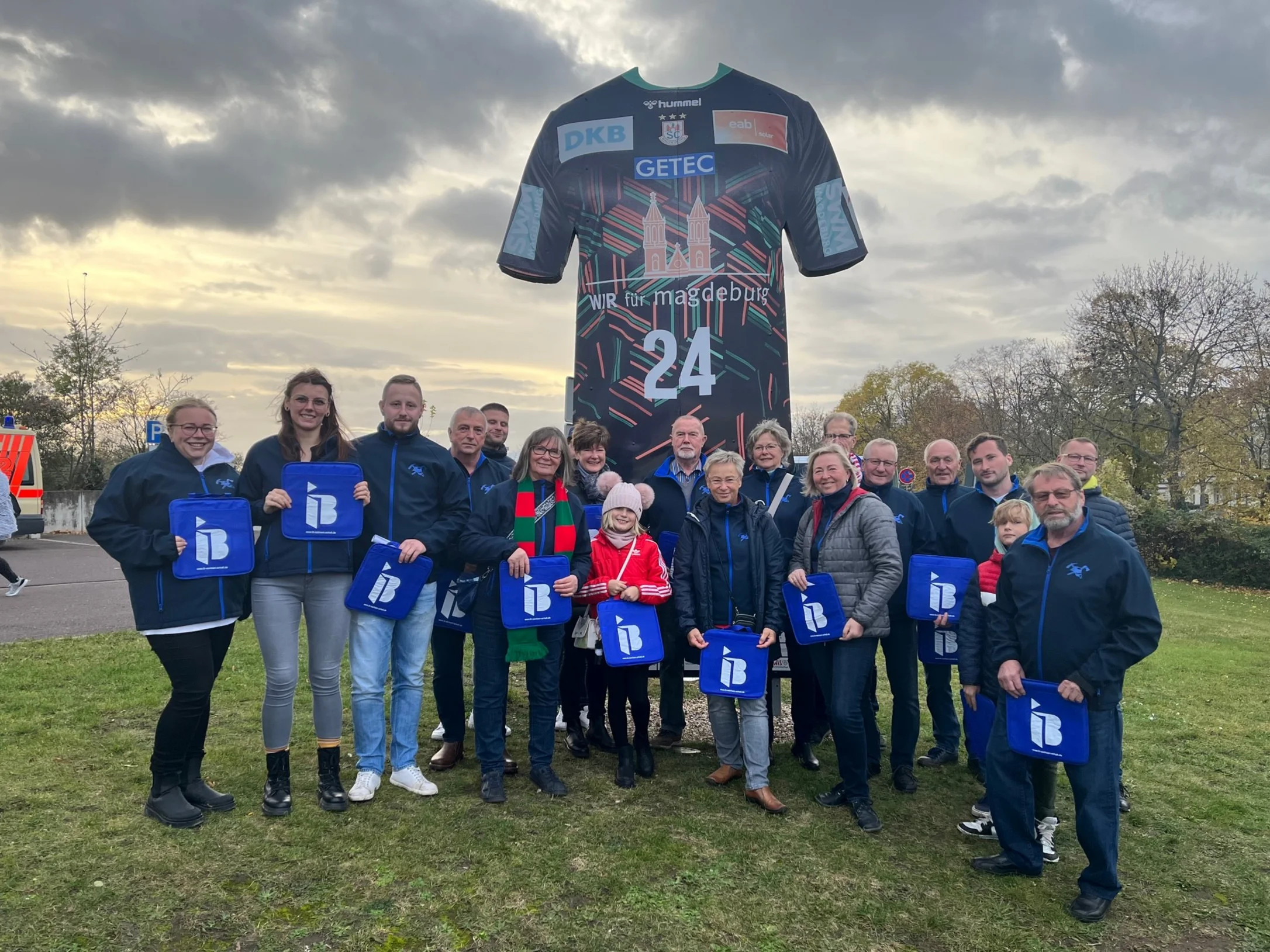 Mitglieder des Förderverein Schernickau mit IB-Logos in der Hand vor einer Arena in Magdeburg