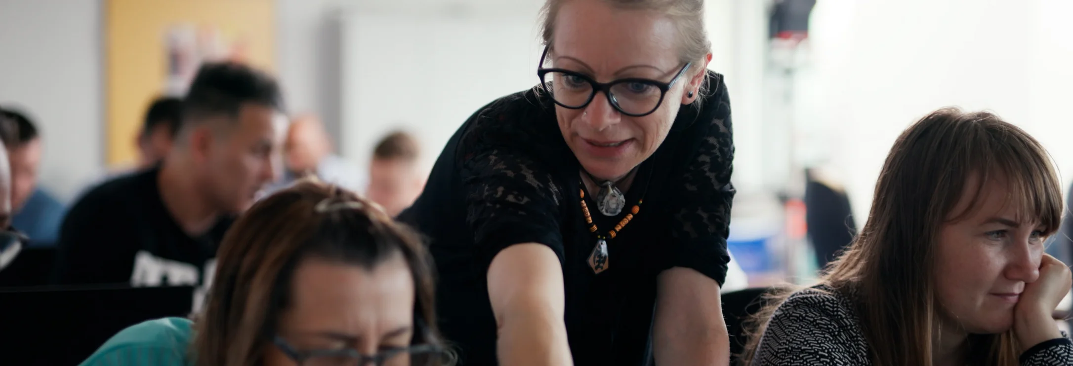 Ein Frau erklärt einer weiteren etwas auf ihrem Laptop