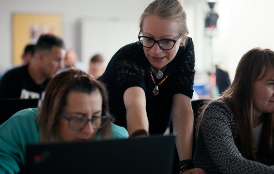 Ein Frau erklärt einer weiteren etwas auf ihrem Laptop