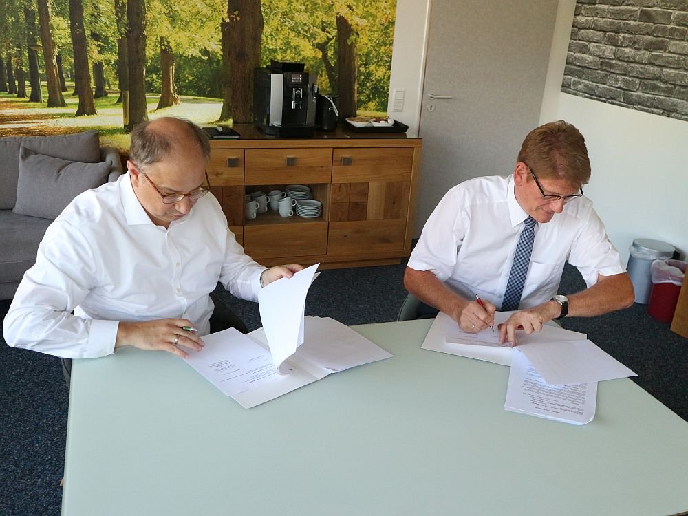 Marc Melzer, Geschäftsleiter der IB und Jens Eckhardt, Vorstandsvorsitzender der Stadtsparkasse Magdeburg, sitzen an einem Tisch und unterzeichnen den Vertrag. Foto: IB
