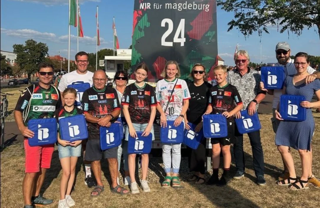 Mitglieder des SV Langenstein von 1932 e.V. mit IB-Logos in der Hand vor einer Arena in Magdeburg