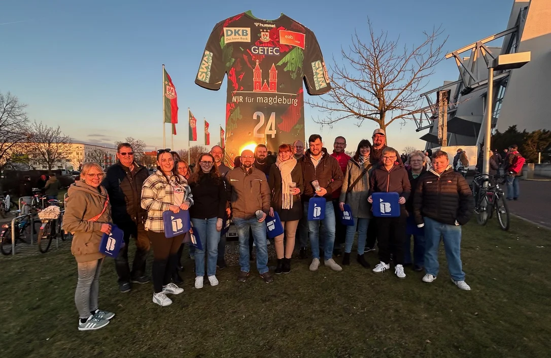 Mitglieder des SV Morsleben 1993 mit IB-Logos in der Hand vor einer Arena in Magdeburg