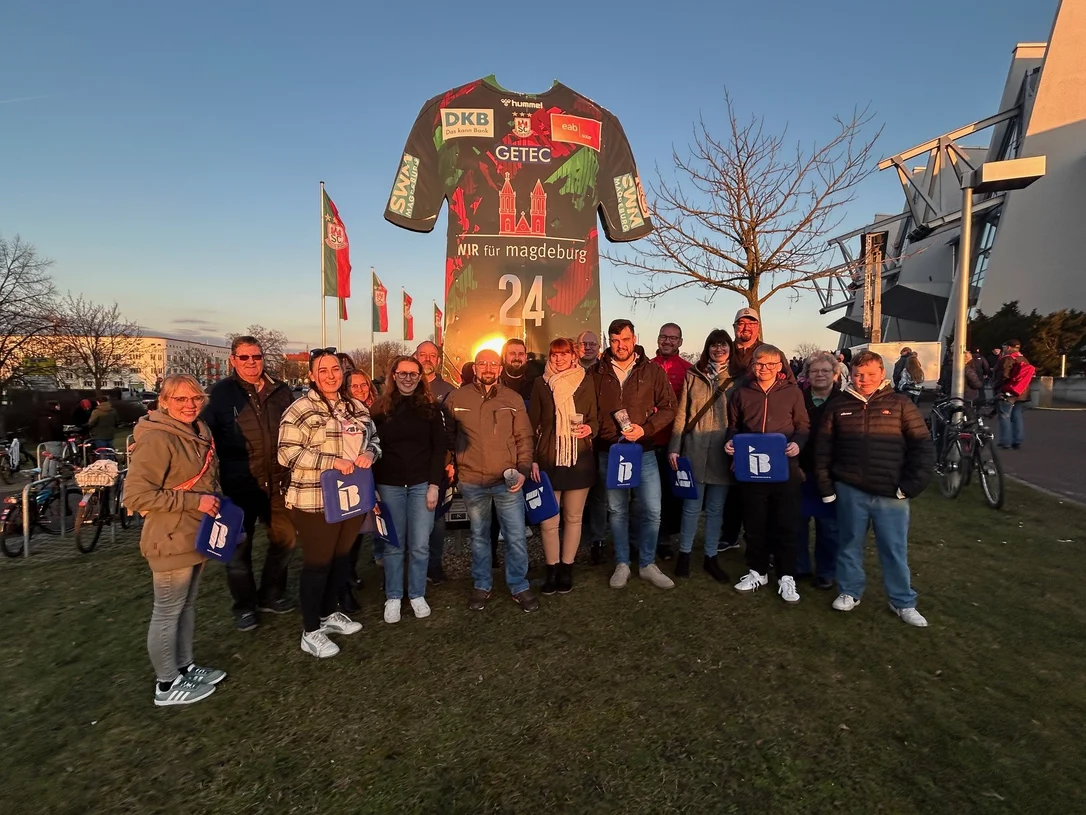 Mitglieder des SV Morsleben 1993 mit IB-Logos in der Hand vor einer Arena in Magdeburg