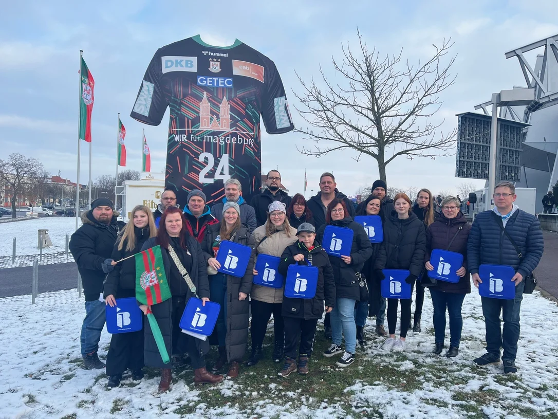 Mitglieder des DRK Kreisverband Börde mit IB-Logos in der Hand vor einer Arena in Magdeburg