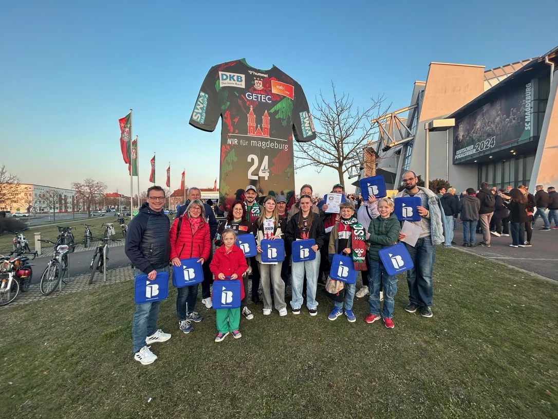 Mitglieder des Fördervereins Randau mit IB-Logos in der Hand vor einer Arena in Magdeburg