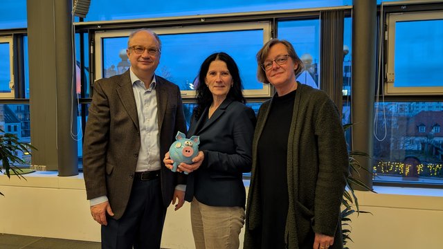 Drei Personen mit Spendenschwein