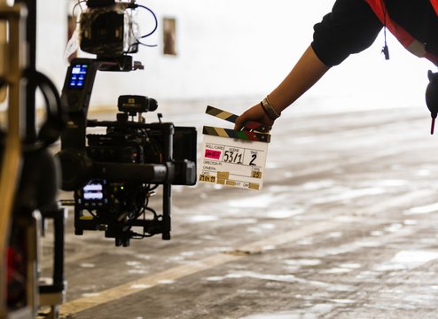 Filmklappe wird vor eine Filmkamera gehalten 