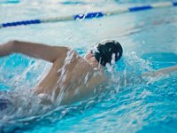 Ein Mann krault im Schwimmbecken