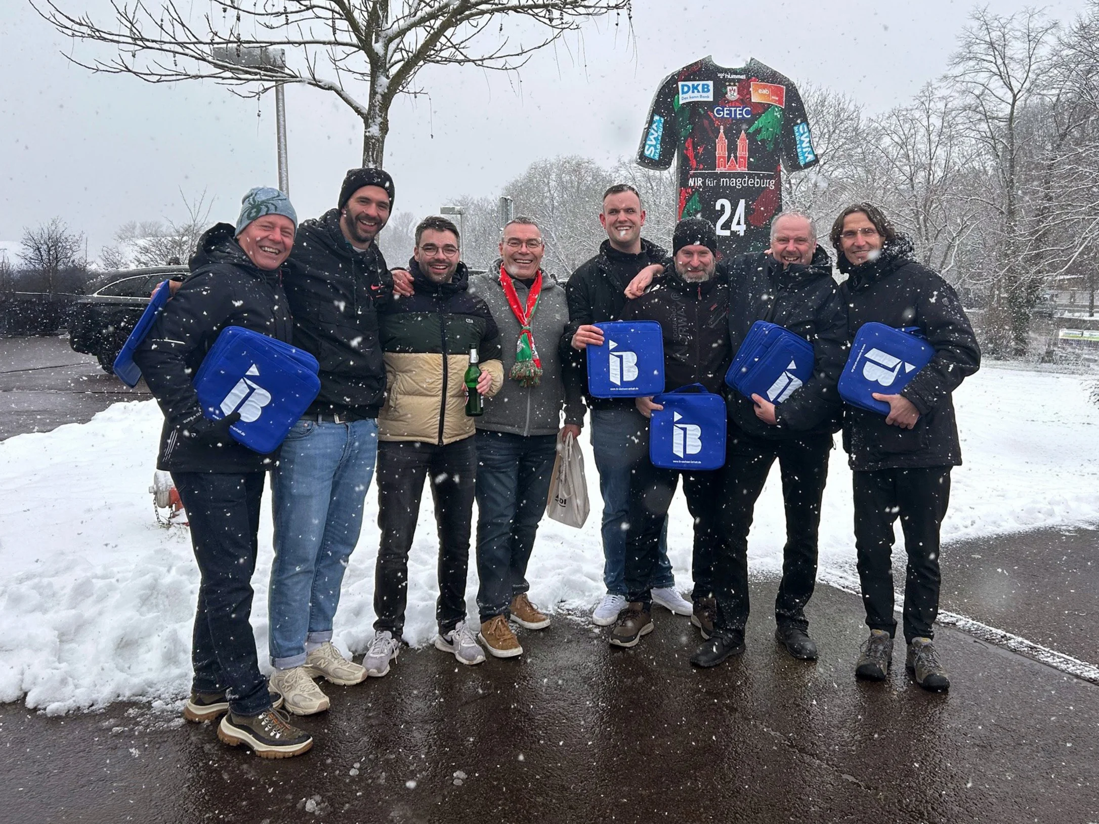 Mitglieder des TTV Locktow mit IB-Logos in der Hand vor einer Arena in Magdeburg