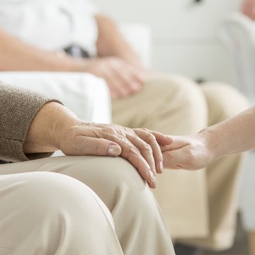 Ältere Person hält die Hand eines jüngeren Menschen