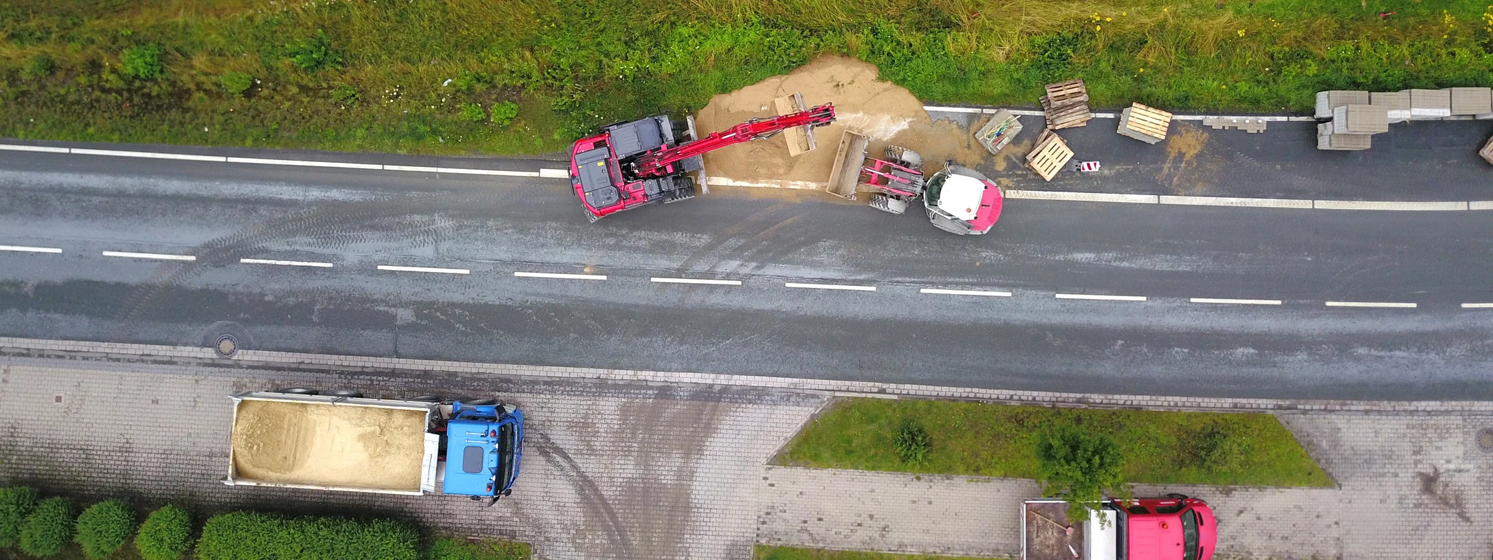 Neben einer Straße wird ein Radweg gebaut. Man sieht Baustellenfahrzeuge. 