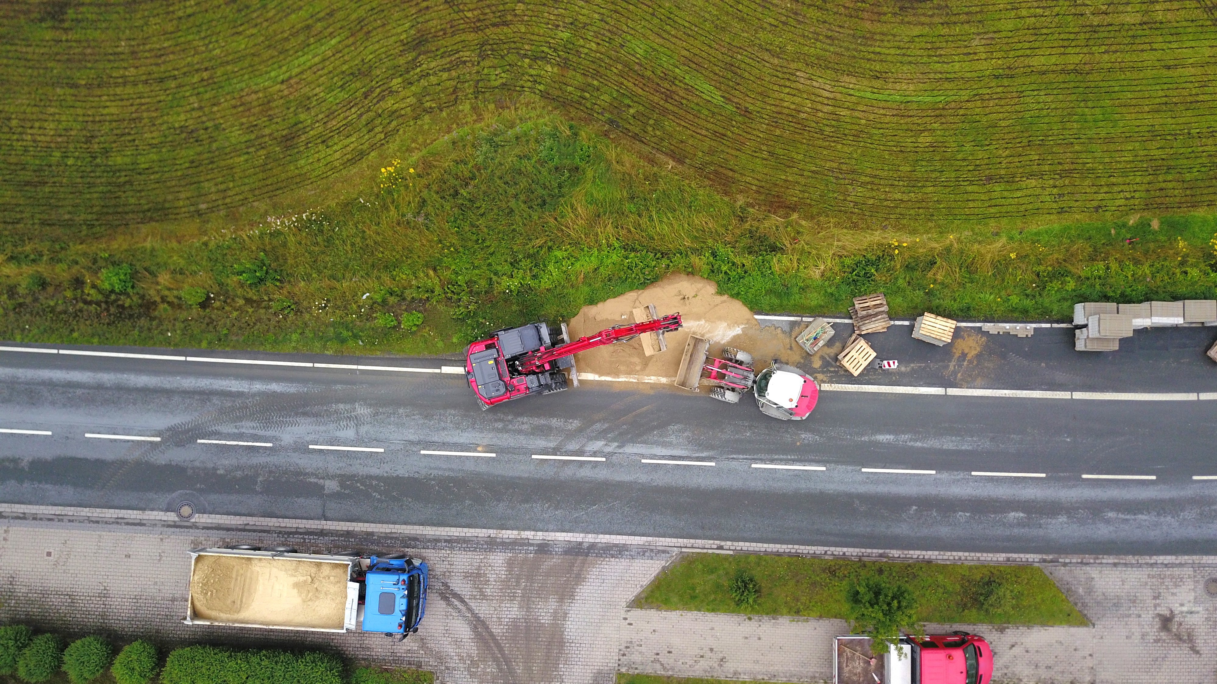 Neben einer Straße wird ein Radweg gebaut. Man sieht Baustellenfahrzeuge. 