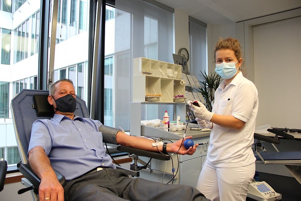 Auf dem Bild zu sehen ist der IB-Mitarbeiter Andreas Knaak bei der Blutspende. Neben ihm steht eine Mitarbeiterin der Uni-Blutbank.